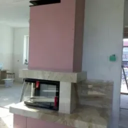 Surowy kominek z marmurową obudową w trakcie montażu w Krakowie, widoczny szkielet konstrukcji z płyt kartonowo-gipsowych.