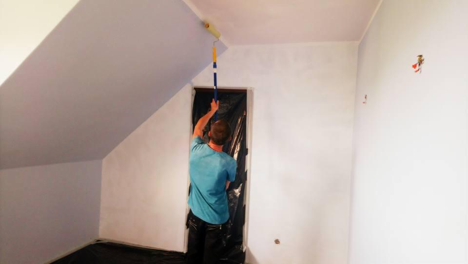 Malowanie sufitu w skosach wałkiem na teleskopowym kiju, zabezpieczone folią drzwi, remont poddasza.
