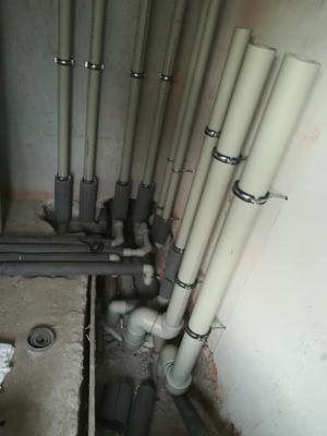 Wewnętrzna instalacja rur pionowych i poziomych z obejmami, częściowo z izolacją, w surowym stanie wykończenia wnętrza.