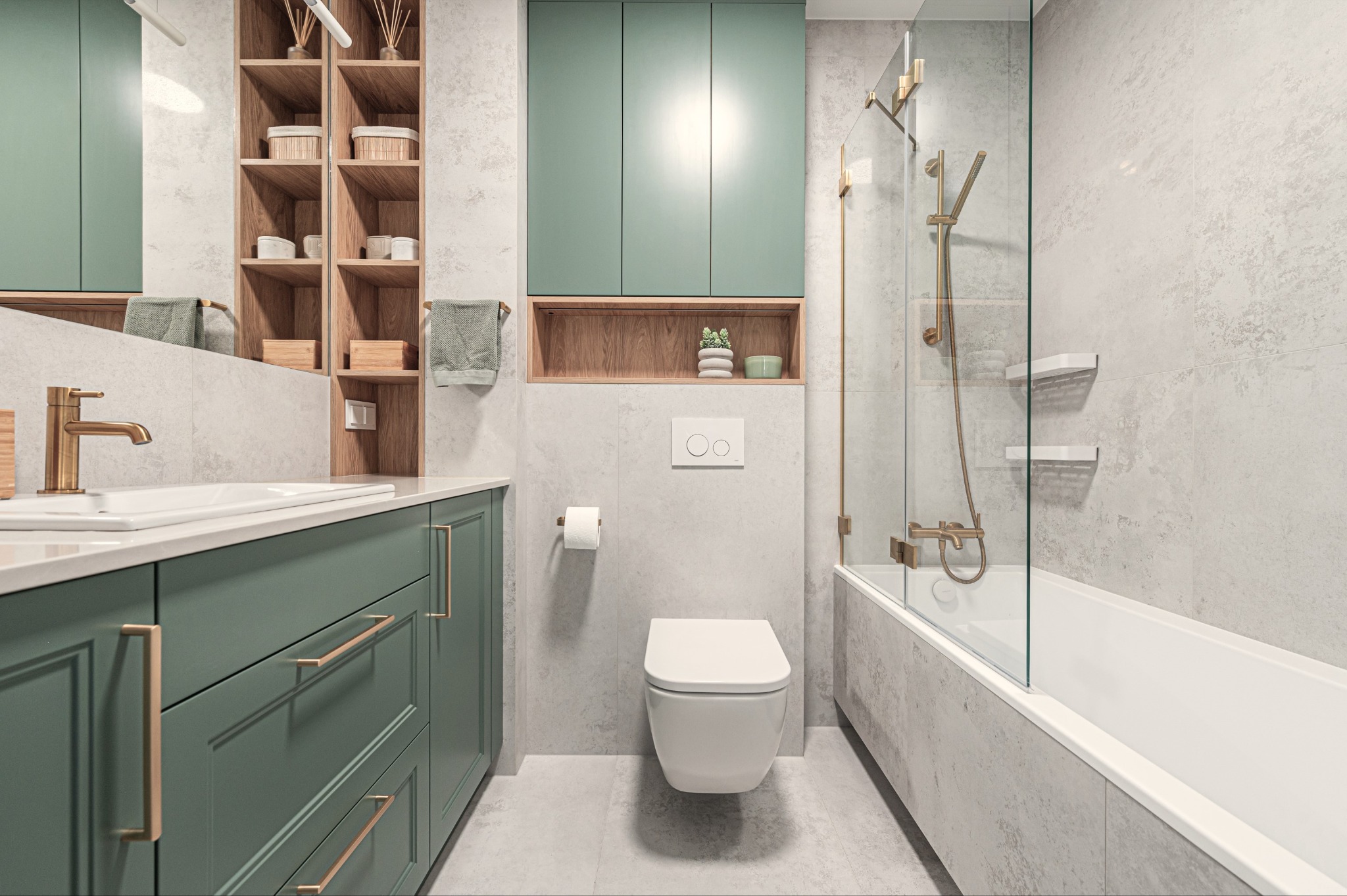 Stylowa łazienka w odcieniach szarości i zieleni. Umywalka z szafką, toaleta, wanna z parawanem, drewniane półki. Złote detale armatury i uchwytów.