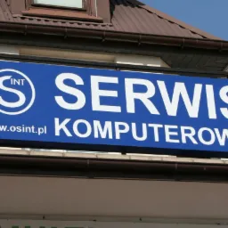 Niebieski szyld z napisem 'SERWIS KOMPUTEROWY' i adresem strony internetowej www.osint.pl umieszczony nad wejściem do budynku z brązowym dachem.