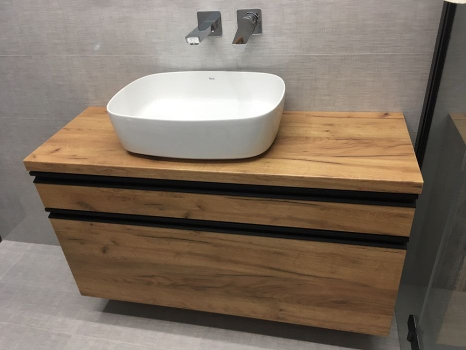 Nowoczesna łazienka z drewnianą szafką pod umywalką, minimalistyczna armatura, szare płytki na ścianie i podłodze.