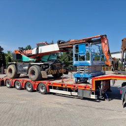 FUH DACHTEX TOMASZ KOWALSKI - Transport specjalistyczny: pomarańczowy wiertniczy pojazd Manitou i niebieski podnośnik nożycowy na czerwonej platformie niskopodwoziowej, błękitne niebo w tle.