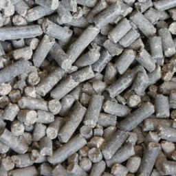 Zbliżenie na szare, cylindryczne granulki nawozu organicznego, z widocznymi nierównościami i pęknięciami, ukazujące ich teksturę i strukturę.