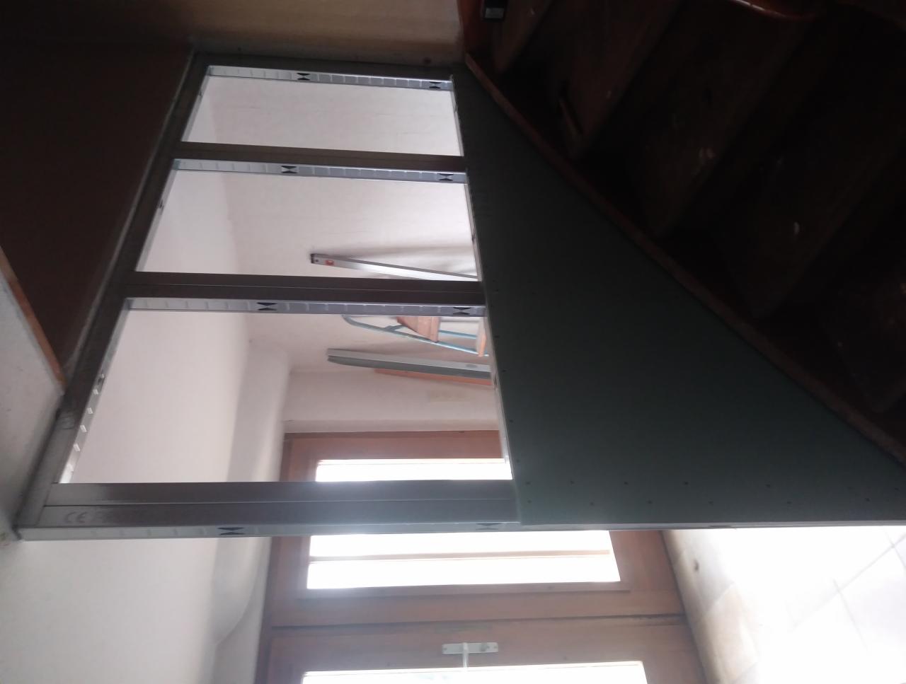 Stelaż metalowy pod konstrukcję z płyty gipsowo-kartonowej, widok od dołu, z fragmentem płyty przymocowanej do skosu pod schodami.