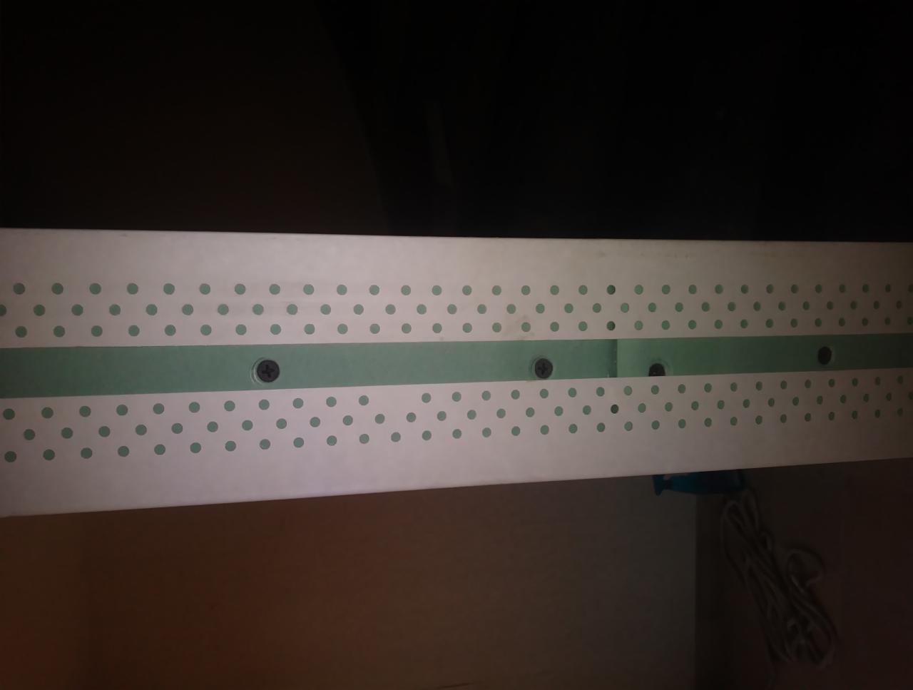 Fragment zamocowanej płyty gipsowo-kartonowej z widocznymi wkrętami i zieloną taśmą wzmacniającą na łączeniu płyt.