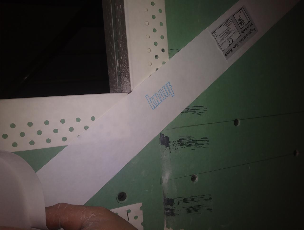 Przygotowanie narożnika ściany z płyty gipsowo-kartonowej za pomocą taśmy wzmacniającej Knauf, widoczne otwory po wkrętach.