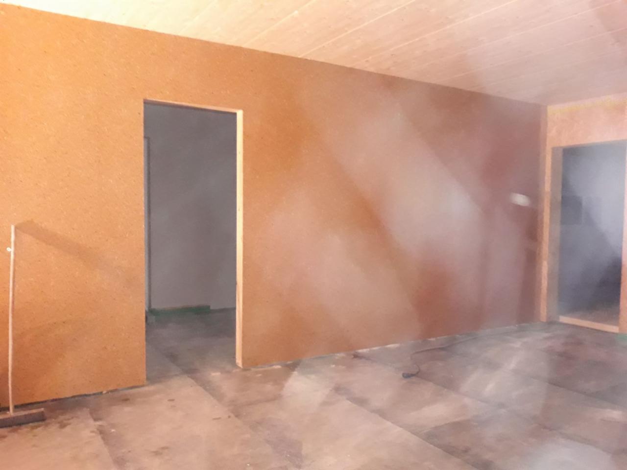 Wnętrze pokoju z zamontowanymi płytami na ścianach i suficie, widoczne otwory drzwiowe, surowy stan wykończenia.