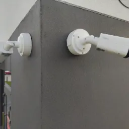 Dwie białe kamery monitoringu marki Dahua zamontowane na rogu budynku z szarą, teksturowaną elewacją.