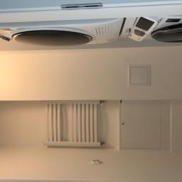 MARBUD - MARIAN SKOTNIK - Minimalistyczna, biała łazienka z pralką i suszarką w zabudowie, grzejnik drabinkowy i ukryte drzwiczki rewizyjne.