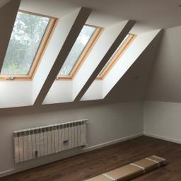 MARBUD - MARIAN SKOTNIK - Poddasze z trzema oknami dachowymi, grzejnikiem osłoniętym folią ochronną i częściowo ułożoną podłogą z paneli w opakowaniu.