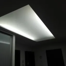 Prostokątny sufit podwieszany z oświetleniem LED, widoczny fragment szafy przesuwnej i ciemne drzwi w tle.