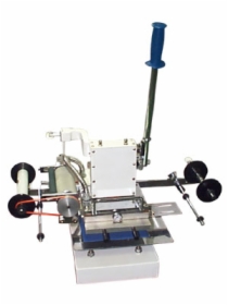 Maszyna introligatorska do foliowania z niebieską rączką, widoczne rolki folii i elementy robocze.