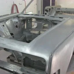 Karoseria klasycznego samochodu po obróbce ściernej, przygotowana do malowania, widoczne ślady po usunięciu starej powłoki w warsztacie.