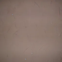 Brązowa ściana z nałożoną fakturą, widoczne ślady narzędzi i drobne niedoskonałości, fragment futryny po prawej stronie.