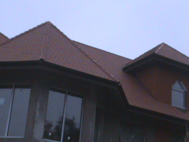 Nowy, brązowy dach z dachówki ceramicznej na domu w Sobolewie, widoczny fragment elewacji z oknami.