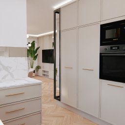 Pil-dom,Paweł Subotkiewicz - Nowoczesna kuchnia z białymi szafkami, marmurowym blatem i zabudowaną kuchenką mikrofalową oraz piekarnikiem Samsung, widok na salon z telewizorem i roślinami doniczkowymi.
