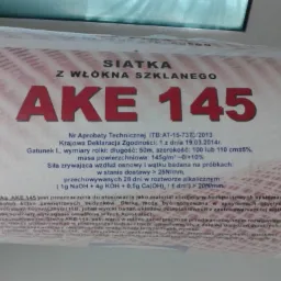 Rolka siatki z włókna szklanego AKE 145 z widocznymi informacjami technicznymi i aprobatami, przeznaczona do systemów ociepleń ścian zewnętrznych.