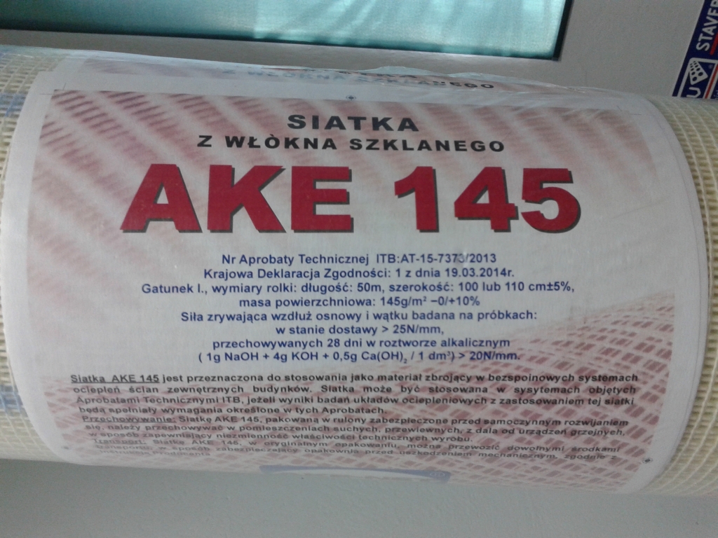 Rolka siatki z włókna szklanego AKE 145 z widocznymi informacjami technicznymi i aprobatami, przeznaczona do systemów ociepleń ścian zewnętrznych.