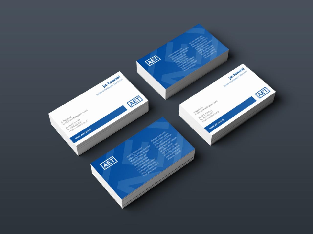 Cztery stosy wizytówek firmy AET ułożone na ciemnoszarym tle, prezentujące dane kontaktowe i zakres działalności.