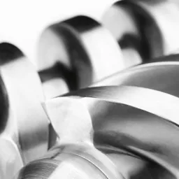 Szczegółowe zbliżenie na metalowy ślimak podajnika, widoczne precyzyjne wykonanie i gładka powierzchnia, oświetlenie podkreśla kształt spirali.