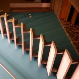 Nowoczesne schody z drewnianymi stopniami i metalową balustradą, widok z góry, błękitna ściana i wzorzysta podłoga w tle.