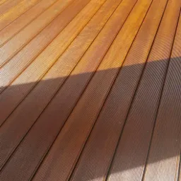 Świeżo polakierowany parkiet z egzotycznego drewna w ciepłym odcieniu brązu, z widocznymi delikatnymi rowkami i odbiciem światła słonecznego.