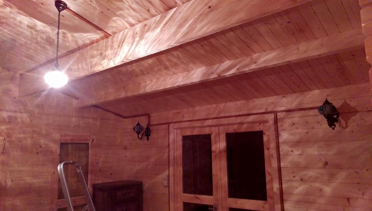 Drewniane wnętrze z zamontowanymi lampami: wisząca kula i dwa kinkiety w stylu marokańskim, widoczna drabina aluminiowa.