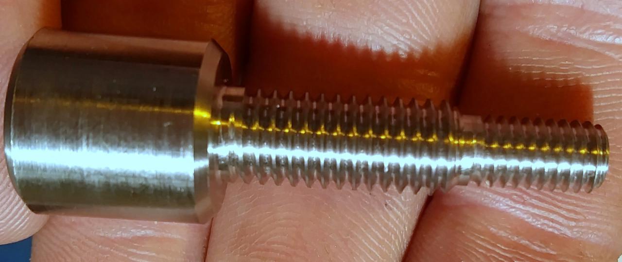 Metalowy śruba z gwintem, trzymana w palcach, ukazująca precyzję wykonania i detale obróbki.