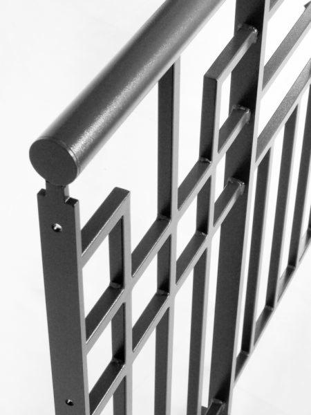 Metalowa balustrada schodowa o geometrycznym wzorze, spawana z profili kwadratowych i okrągłych, pomalowana na ciemny kolor, widoczne spawy.