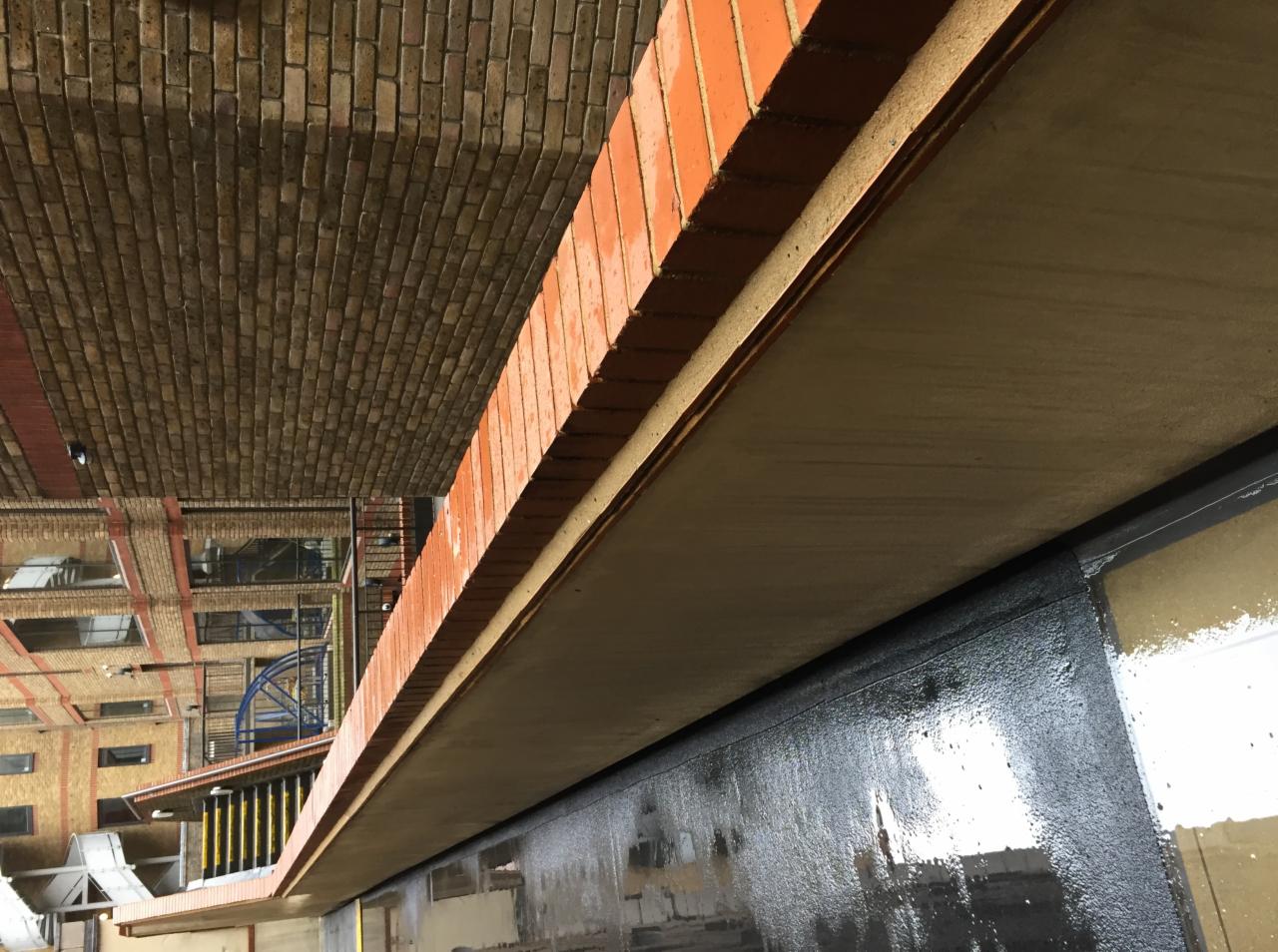 Wnętrze budynku po malowaniu, widoczne ślady farby na oknach i ścianach, ceglany sufit.