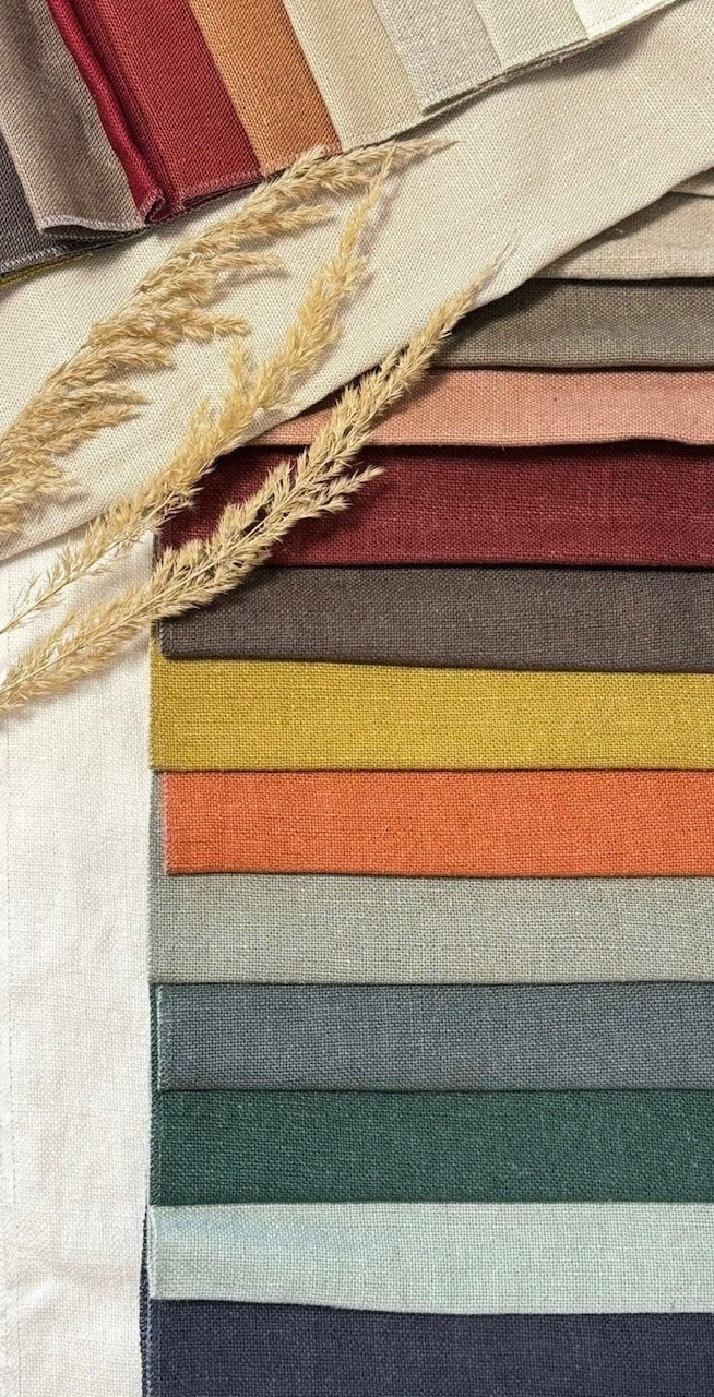 Próbki tkanin w różnych kolorach ułożone warstwowo, z dekoracyjnym suszem w rogu, prezentacja palety barw.