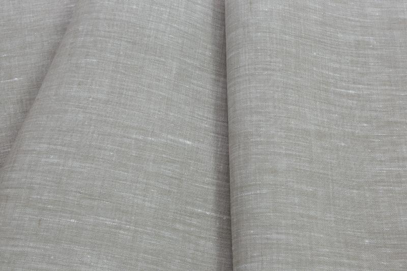 Szczegółowe ujęcie lnianej tkaniny w odcieniach szarości, z widoczną fakturą włókien i delikatnym załamaniem światła na fałdzie materiału.