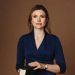 Portret adwokatki w granatowej sukience, trzymającej starą książkę w zielonej oprawie, na brązowym tle.