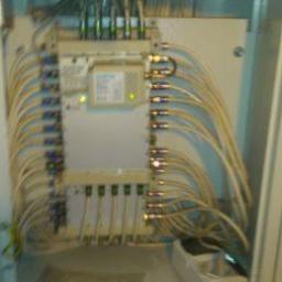 el4you - Rozdzielnica elektryczna w metalowej obudowie z licznymi kablami podłączonymi do złączek, widoczne diody sygnalizacyjne.