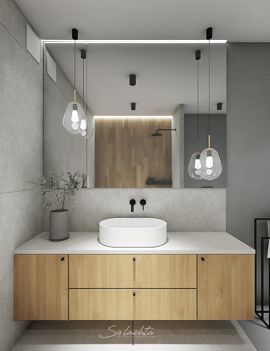 Nowoczesna łazienka z drewnianą szafką pod umywalką, owalną białą umywalką nablatową, czarną armaturą, lustrem na całą ścianę i wiszącymi lampami z przezroczystego szkła.