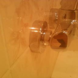 Maksim Halushka MaxiSoft - Błyszcząca, chromowana bateria umywalkowa zamontowana na beżowej ścianie z płytek w łazience, widoczna z bliska pod kątem.