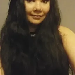 Portret kobiety z długimi, ciemnymi włosami i wyrazistym makijażem oczu, delikatny uśmiech.