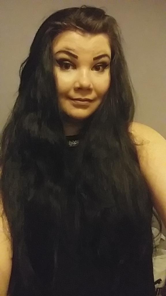 Portret kobiety z długimi, ciemnymi włosami i wyrazistym makijażem oczu, delikatny uśmiech.