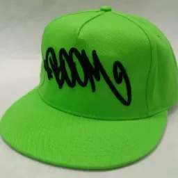 Jasnozielona czapka typu snapback z czarnym, wyhaftowanym napisem 'Boom' na froncie, leżąca na białym tle.