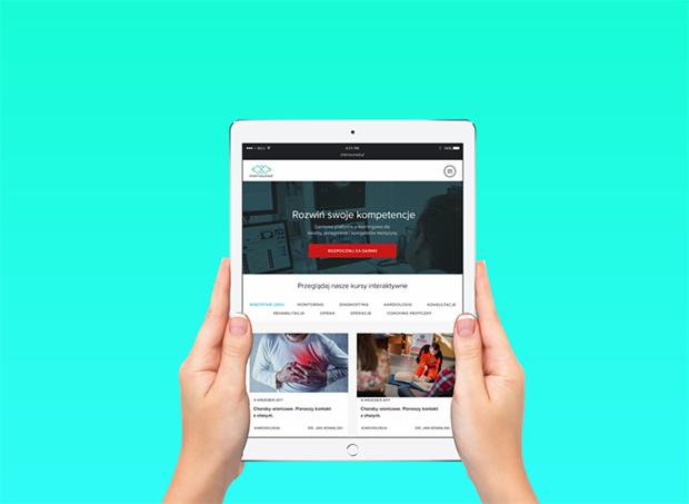 Osoba trzyma tablet prezentujący stronę internetową z ofertą kursów online, w tle jednolity turkusowy kolor.