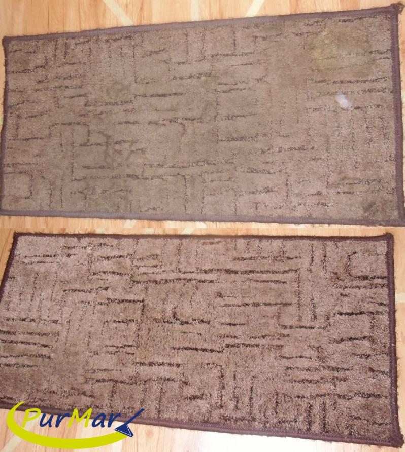 Dwa brązowe dywany z geometrycznym wzorem, ułożone jeden nad drugim na drewnianej podłodze; górny dywan z widocznymi plamami, dolny dywan z logo firmy czyszczącej w lewym dolnym rogu.