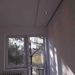 Remont-ownia - Wnętrze pokoju po remoncie z widokiem na okno, z zamontowanymi oknami PCV marki VEKA, z podwieszanym sufitem z oświetleniem punktowym.