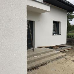 Hetman Bud - Fragment nowo otynkowanego domu jednorodzinnego z widoczną elewacją o fakturze baranka, schody wejściowe i drabina oparta o ścianę.