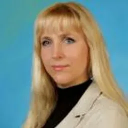 Portret kobiety z blond włosami w beżowej marynarce na tle jasnoniebieskim.