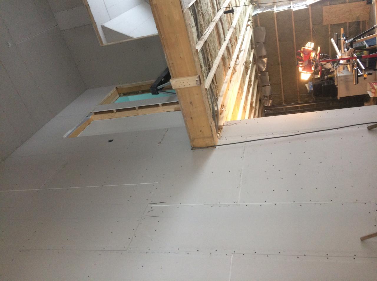 Montaż płyt na ścianie i suficie, widoczne drewniane belki konstrukcyjne i ocieplenie wełną mineralną, przygotowanie do dalszych prac wykończeniowych.