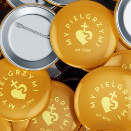 ZBIGNIEW GÓRAL BLENDIFY AI - Stos żółtych przypinek z logo 'MY PIELGRZYMI' i rokiem założenia 2008. Metalowe zapięcia widoczne na srebrnych rewersach. Bliski kadr, ostre światło.