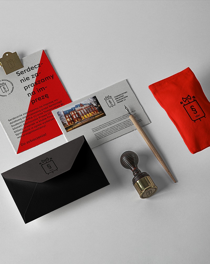 Komplet materiałów promocyjnych: zaproszenie, koperta, pocztówka z budynkiem, pieczęć i woreczek z logo Towarzystwa Biblioteki Słuchaczów Prawa UJ.