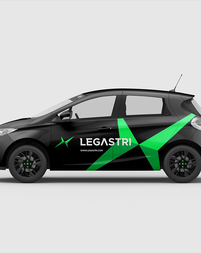 Czarny samochód z zielonym geometrycznym wzorem i nazwą 'LEGASTRI' na boku, prezentujący identyfikację wizualną firmy. Minimalistyczny design, nowoczesny styl.