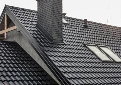 Nowy, ciemny dach z dachówki ceramicznej z trzema oknami dachowymi i ceglanym kominem, widoczny fragment więźby dachowej.